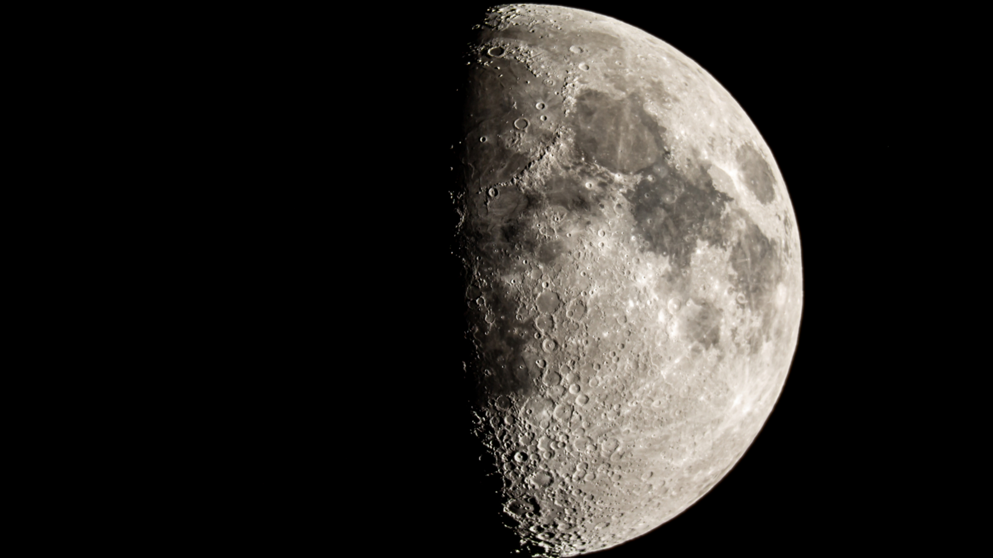 The moon is photographed with its right side lit by sunlight in a black night sky.