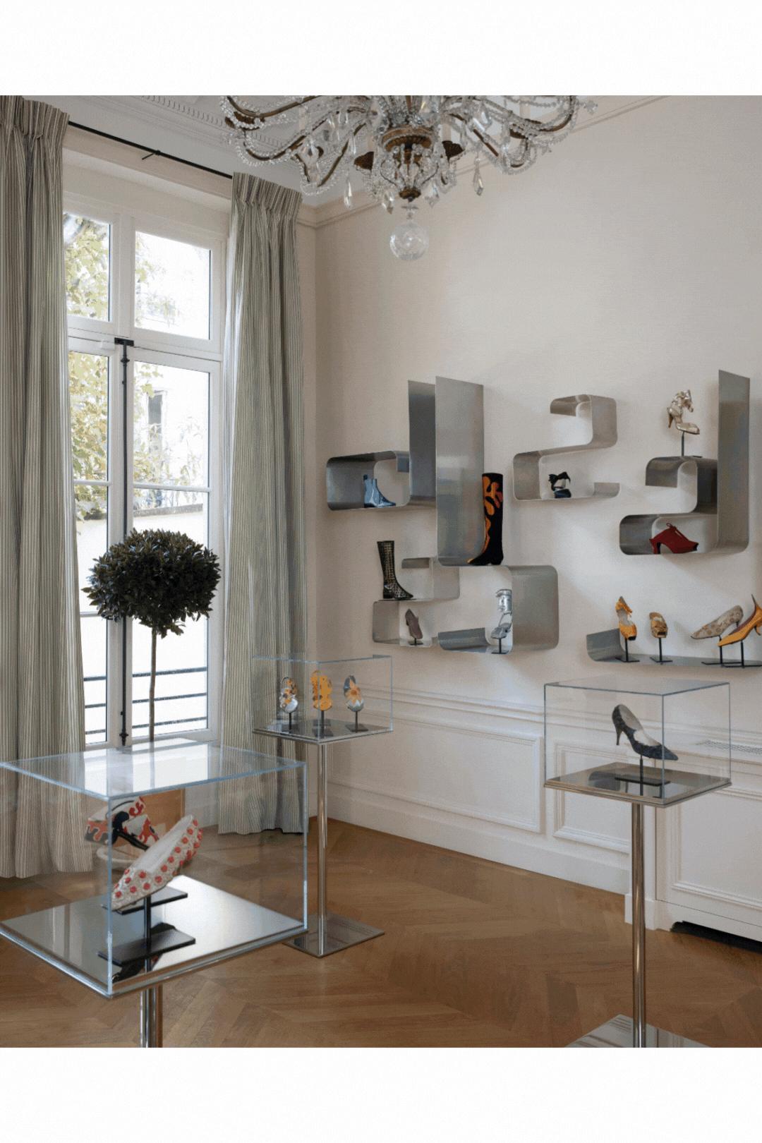 A rotating gif showcasing a luxury shoe fashion brand&#039;s atelier, set within a palatial, wood, chrome, and marble-clad building, and its quirky selection of colorful designs.
