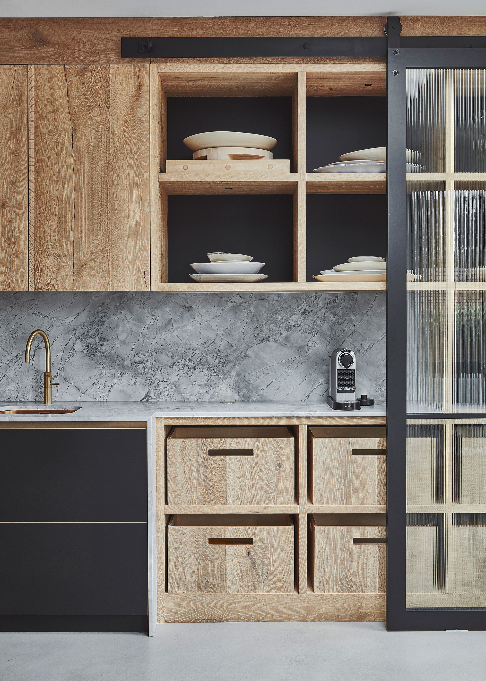 a scandi-style wood kitchen with a reeded glass door