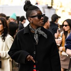 nikki ogunnaike wearing a scarf, a black jacket, and red pants