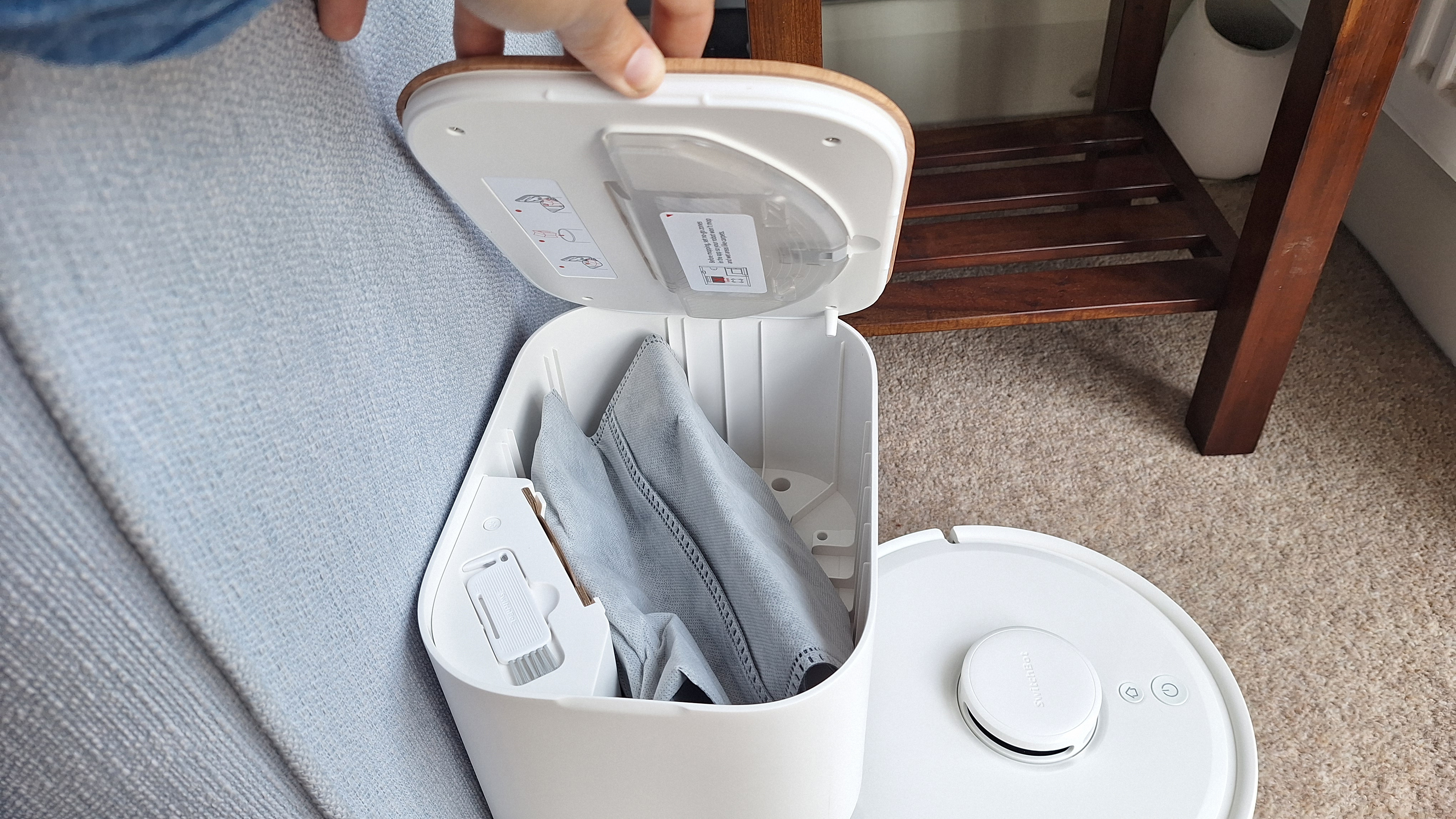 Dock for SwitchBot K11+ robot vacuum with lid removed to show dust bag