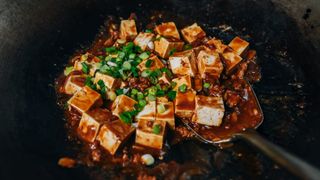 spicy garlic tofu being stir-fried in a wok