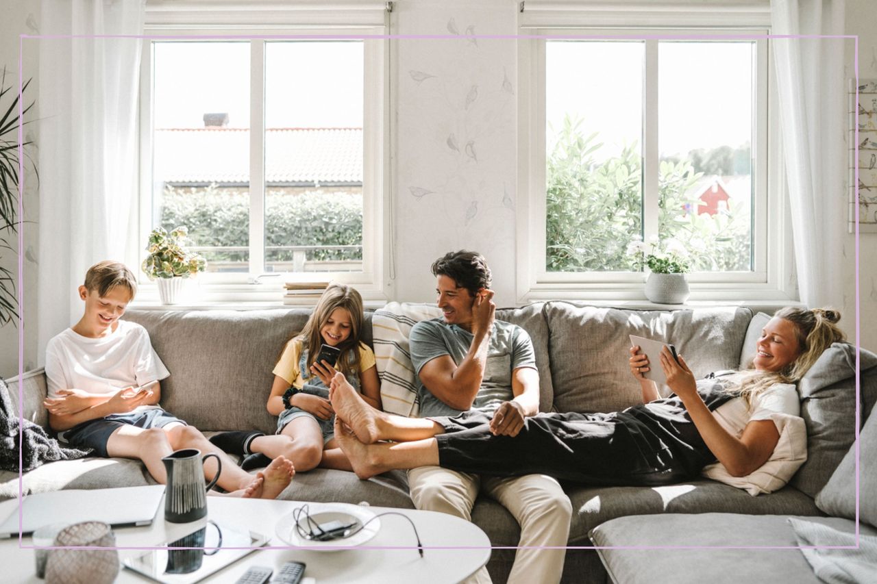 A family sat on a sofa looking at their smartphones