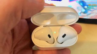 Airpods in case in someone's hand.