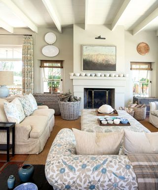 neutral living room with neutral and floral sofas, fireplace and painted beamed ceiling