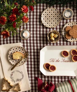 A bird's eye view of festive tableware on a red-and-white checked tablecloth.