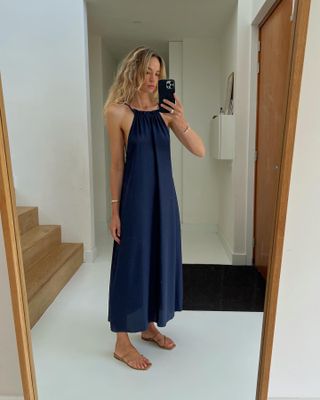 Anouk Yve wearing a navy blue linen midi dress and tan sandals.