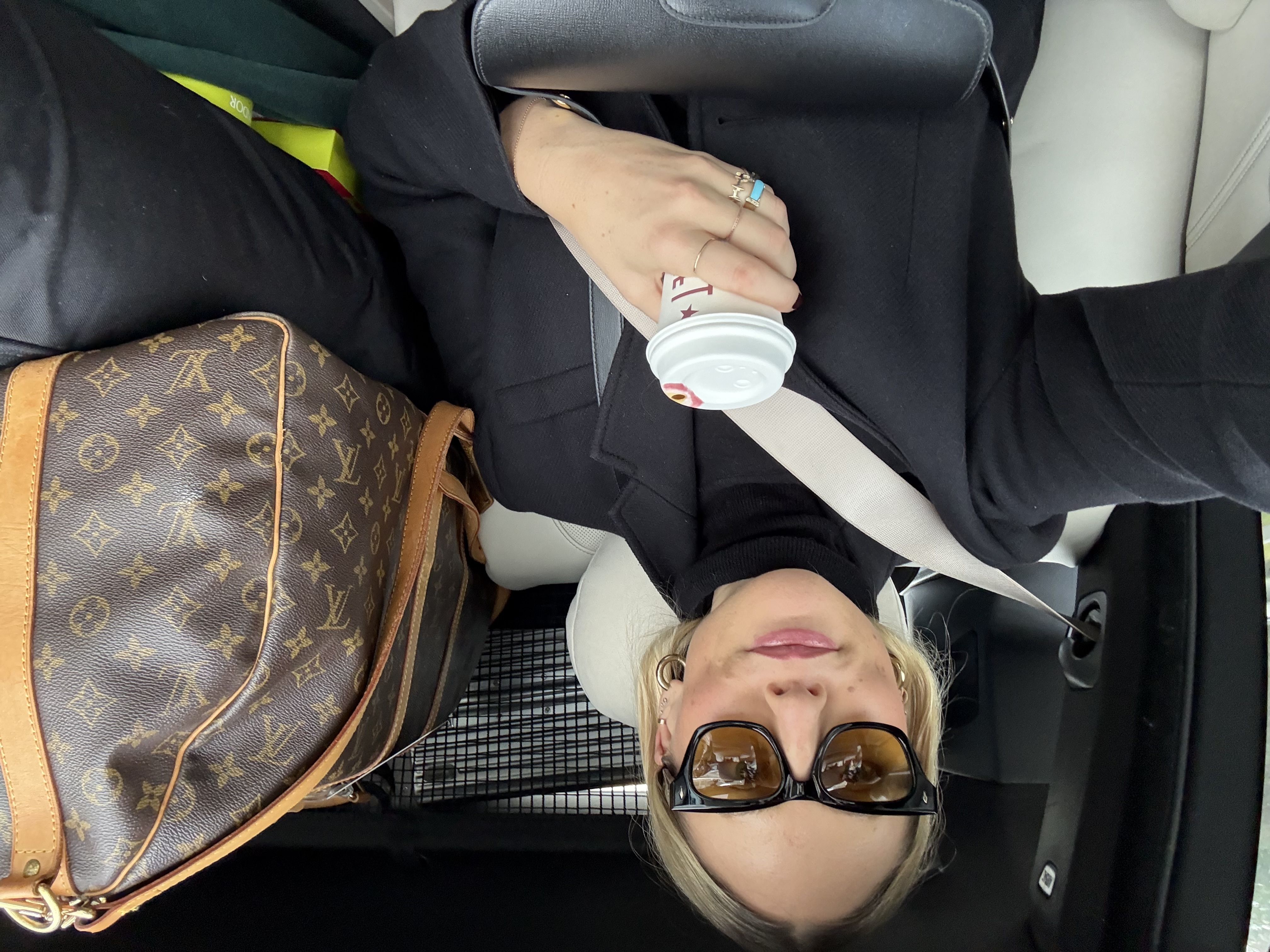 Brooke Ely Danielson takes a selfie in a car with her light-lens sunglasses and Louis Vuitton monogram carry-all