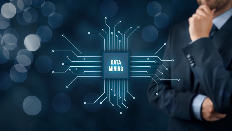 Graphic of data mining being shown on a virtual circuit board beside a businessman 