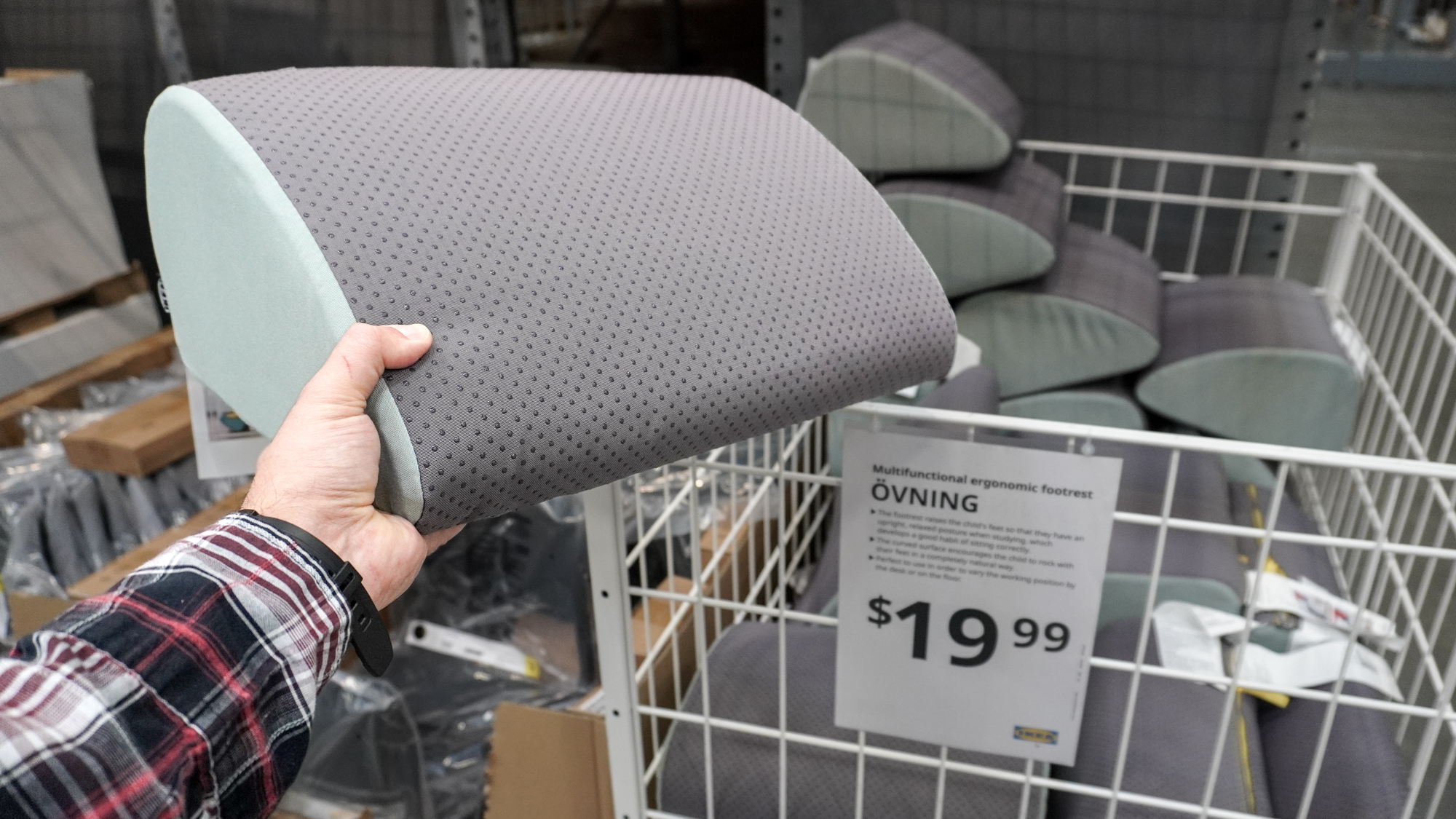 A person holding the &amp;Ouml;VNING ergonomic footrest in hand at IKEA