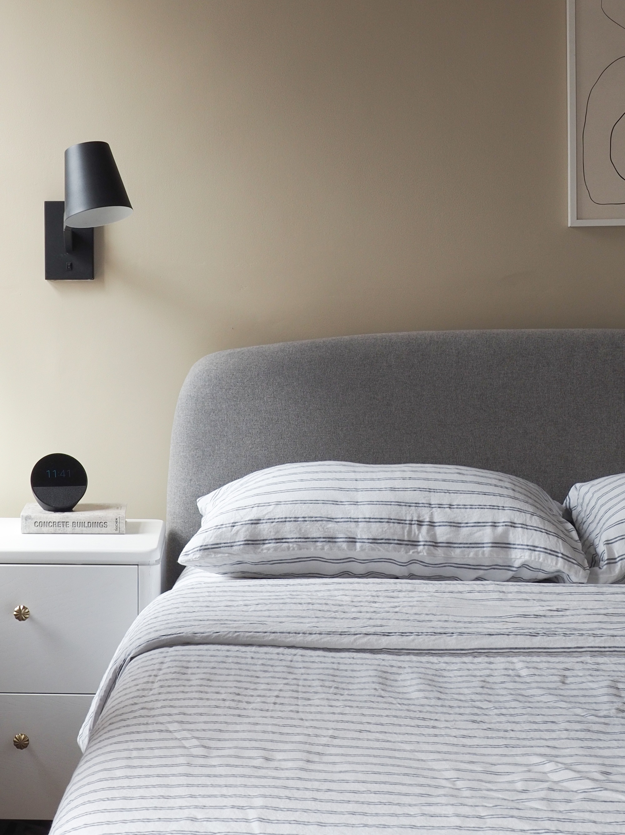 piglet in bed striped bedding on a grey bed in a beige bedroom