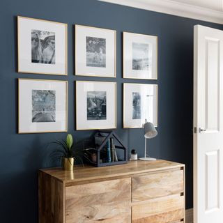 grey wall with picture frames and chest and white door