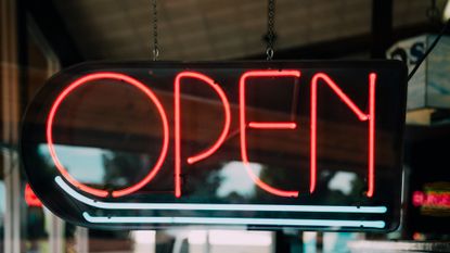 Neon sign says open on a window