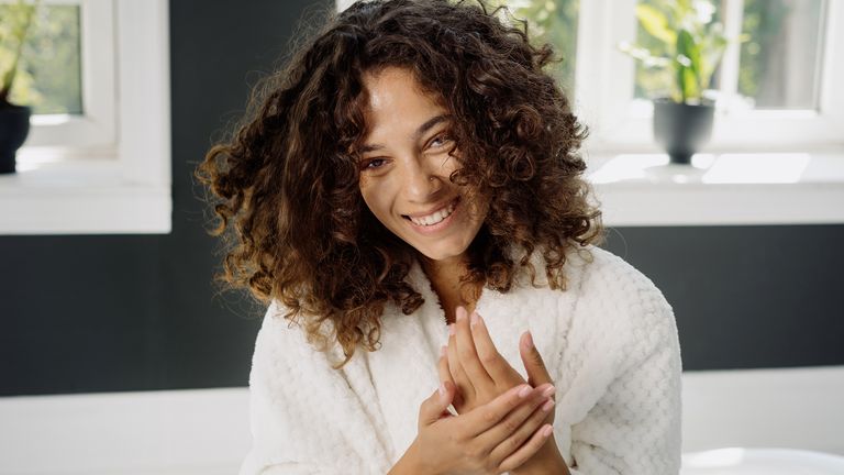 Young adult african american woman in bathrobe spending morning in bathroom - stock photo