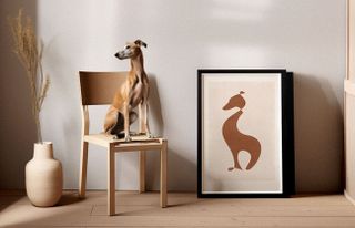A brown greyhound sits in front of a poster of a brown greyhound