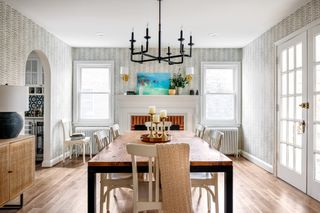 Dining room with wood table, painted chairs, gray patterned wallpaper and wood floor