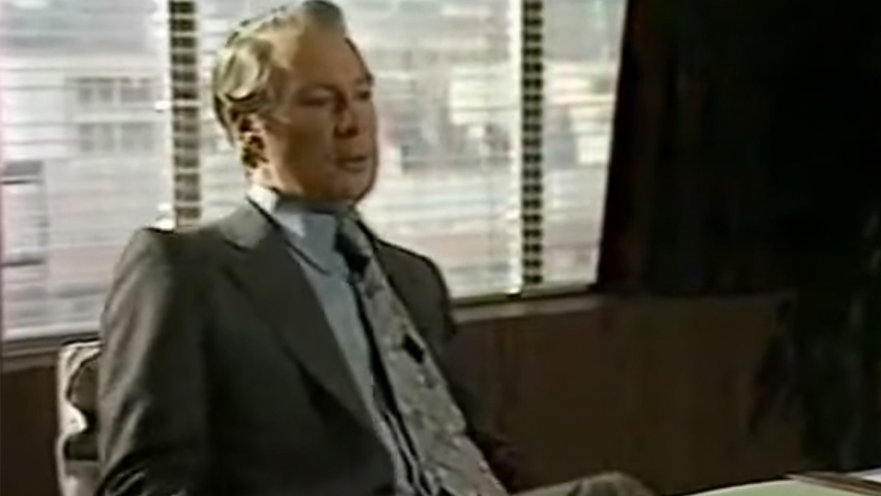 A screenshot of a man in a suit in An Englishman's Castle