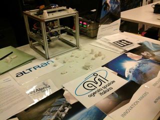 The Altran-built Portable On-Board 3D Printer, a small 3D printer headed for the International Space Station, is seen with examples of objects it can print during 2014 event at the Italian Space Agency. The printer will be delivered to the space station this year.