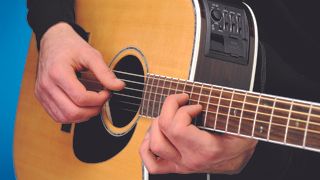 Man plays chord on acoustic guitar