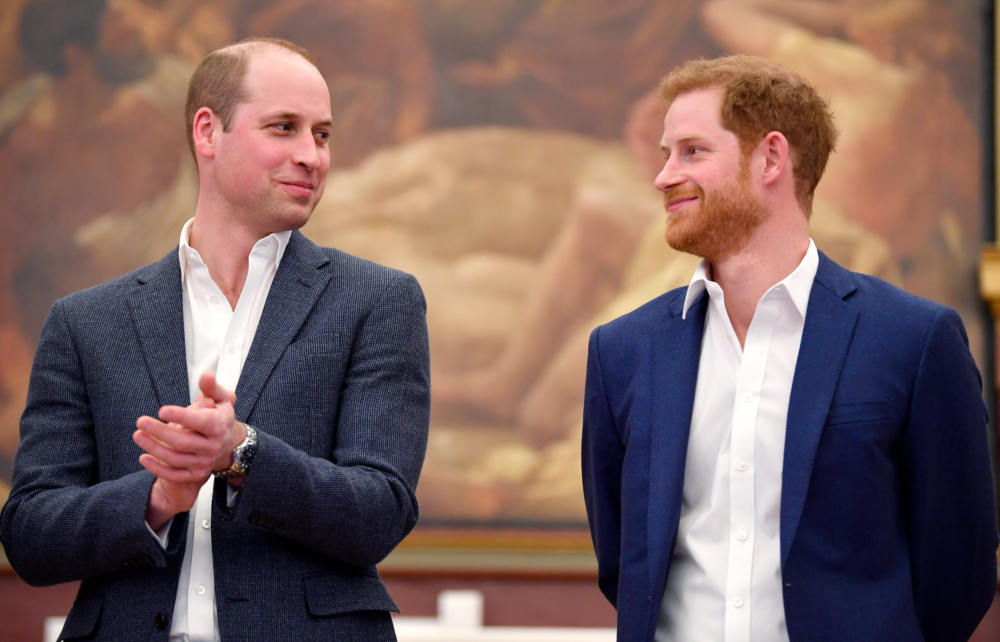 Prince WIlliam clapping and looking at Prince Harry