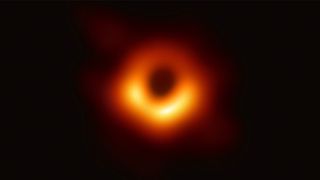 direct image of a supermassive black hole, showing a fuzzy orange ring surrounding a dark circle