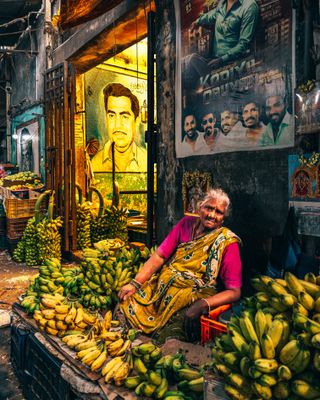 A woman at a market in Asia surrounded by bananas