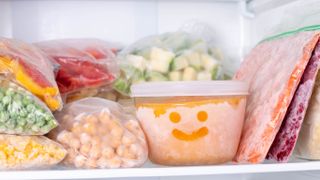 A freezer shelf filled with contained foods and a smiley face drawn on one container