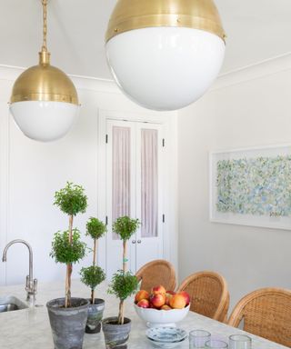 white kitchen with rattan bar stools, colorful artwork and fabric lined pantry doors