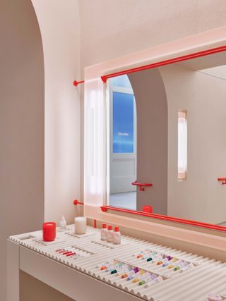 Red-framed mirror above rippled tray of make-up to try at New York Glossier store in SoHo