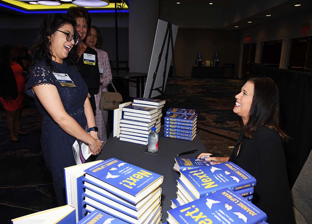 Author Joanne Lipman (r.) signs books for attendees of the WICT Network Leadership Conference at Manhattan&rsquo;s Marriott Marquis.
