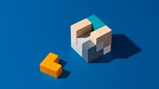 A block with multicolored pieces and the missing piece lying beside it.
