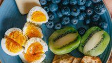 Healthy breakfast plate with blueberries, eggs, crackers, kiwi, and cheese