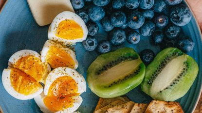 Healthy breakfast plate with blueberries, eggs, crackers, kiwi, and cheese
