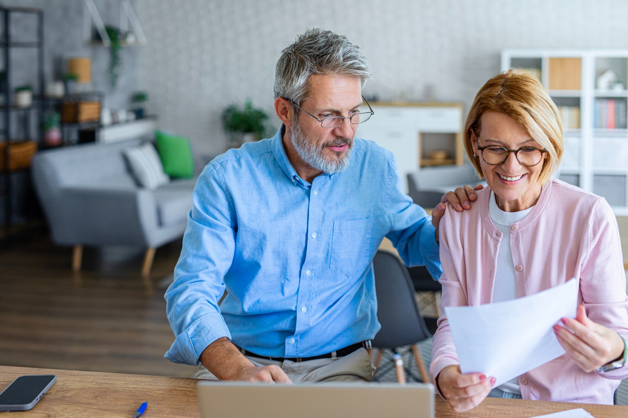 Senior couple reviewing pension insurance documents together at home, representing retirement planning and financial security