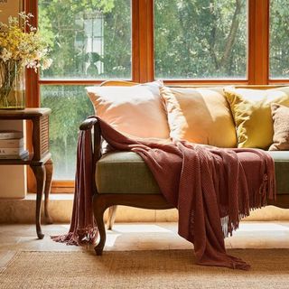 A rust colored throw blanket draped over a couch