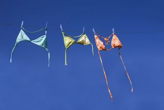 Three bikini tops hanging on a line.