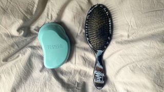 A tangle teezer and wet brush pictured on a bed