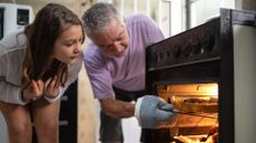 Girl and man checking on turkey in the oven. FG Trade via Getty Images.
