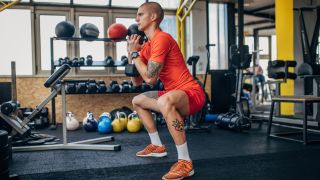 Man performs goblet squat with dumbbell