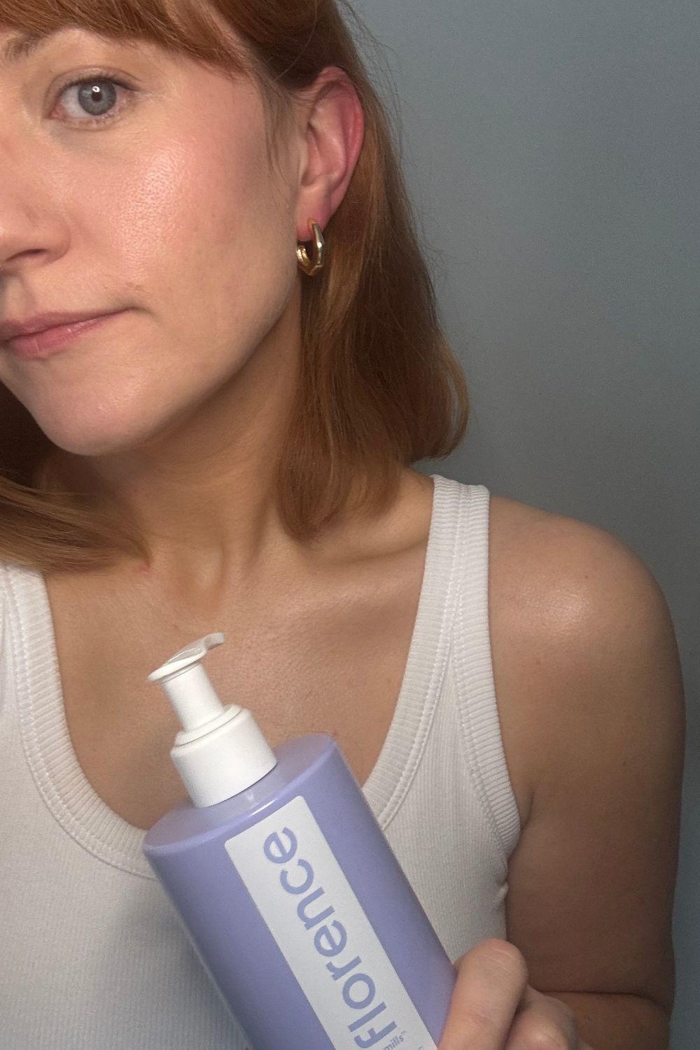 matilda holding a bottle of florence by mills mirror magic illuminating body moisturiser