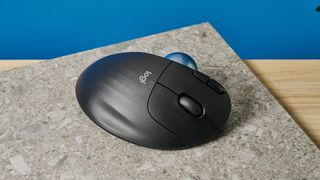 A black Logitech Ergo M575 ergonomic mouse with a teal trackball on the left side