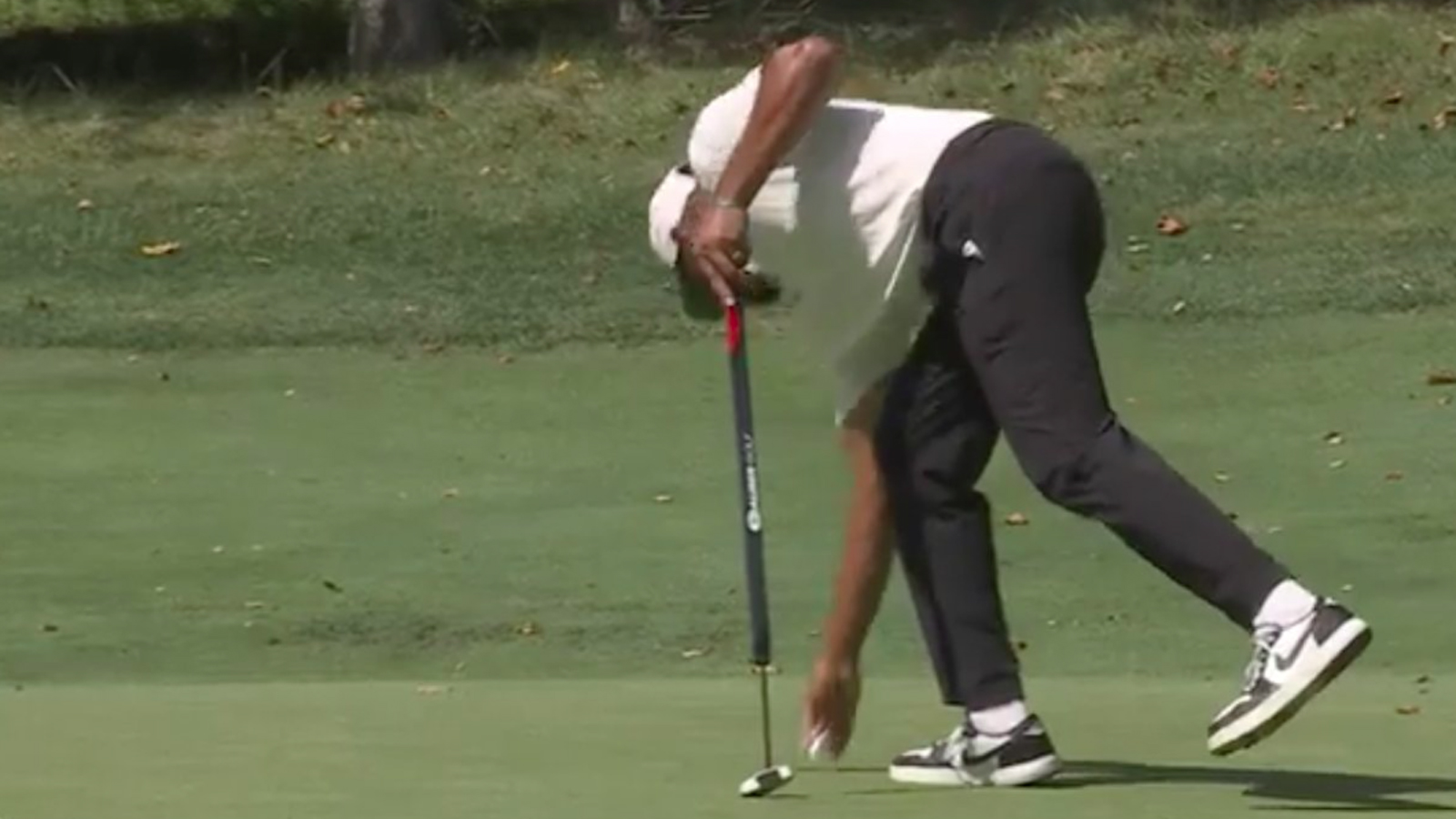 Tony Finau picks up a ball from the hole
