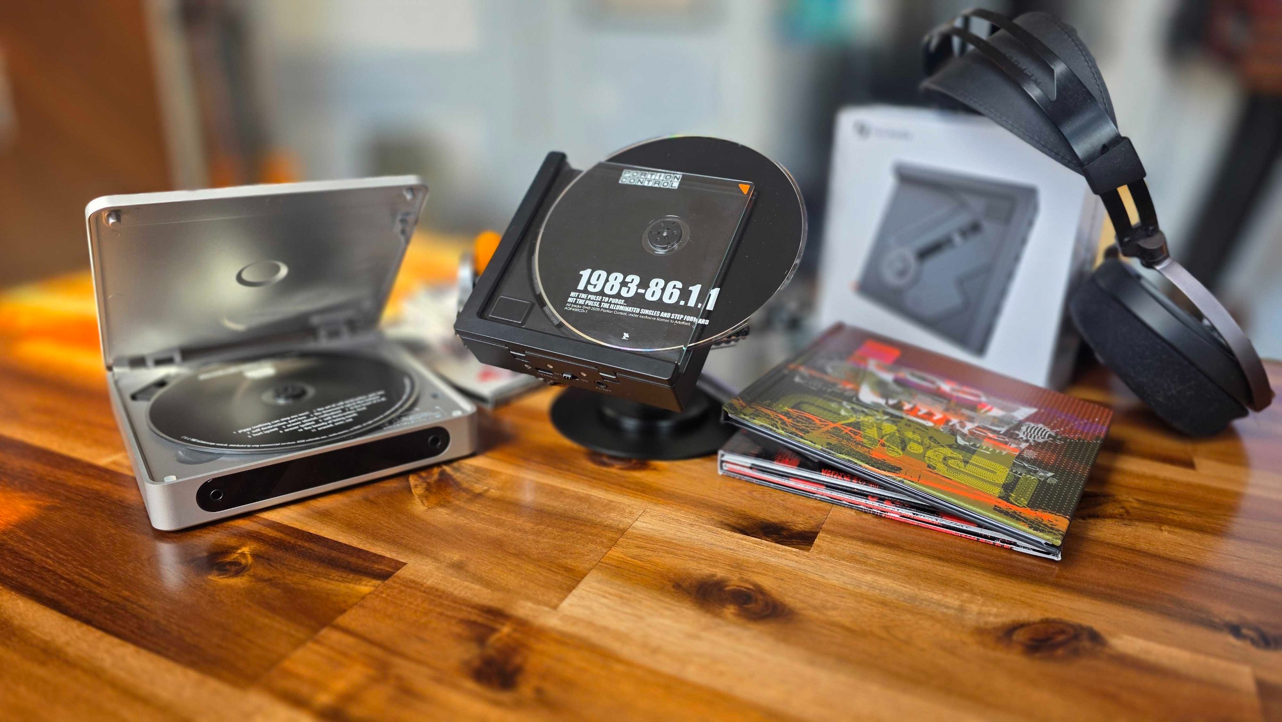 Fiio and Fosi Audio CD players on a table with headphones and CDs