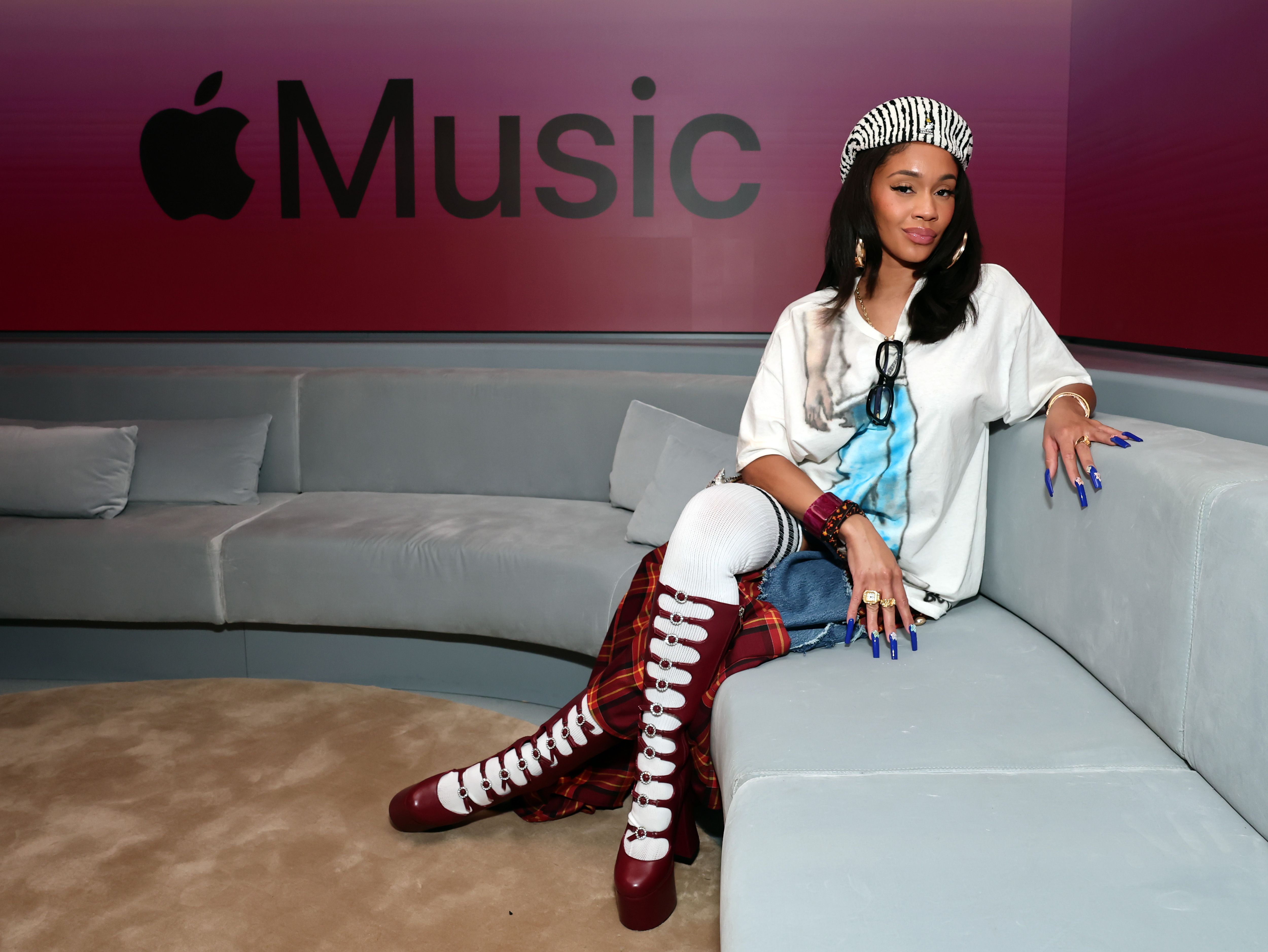 a woman sitting on a couch wearing red boots, a white graphic tee shirt, and a striped beret