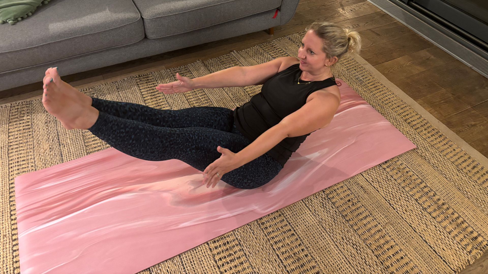 Kat Storr doing boat pose on floor at home