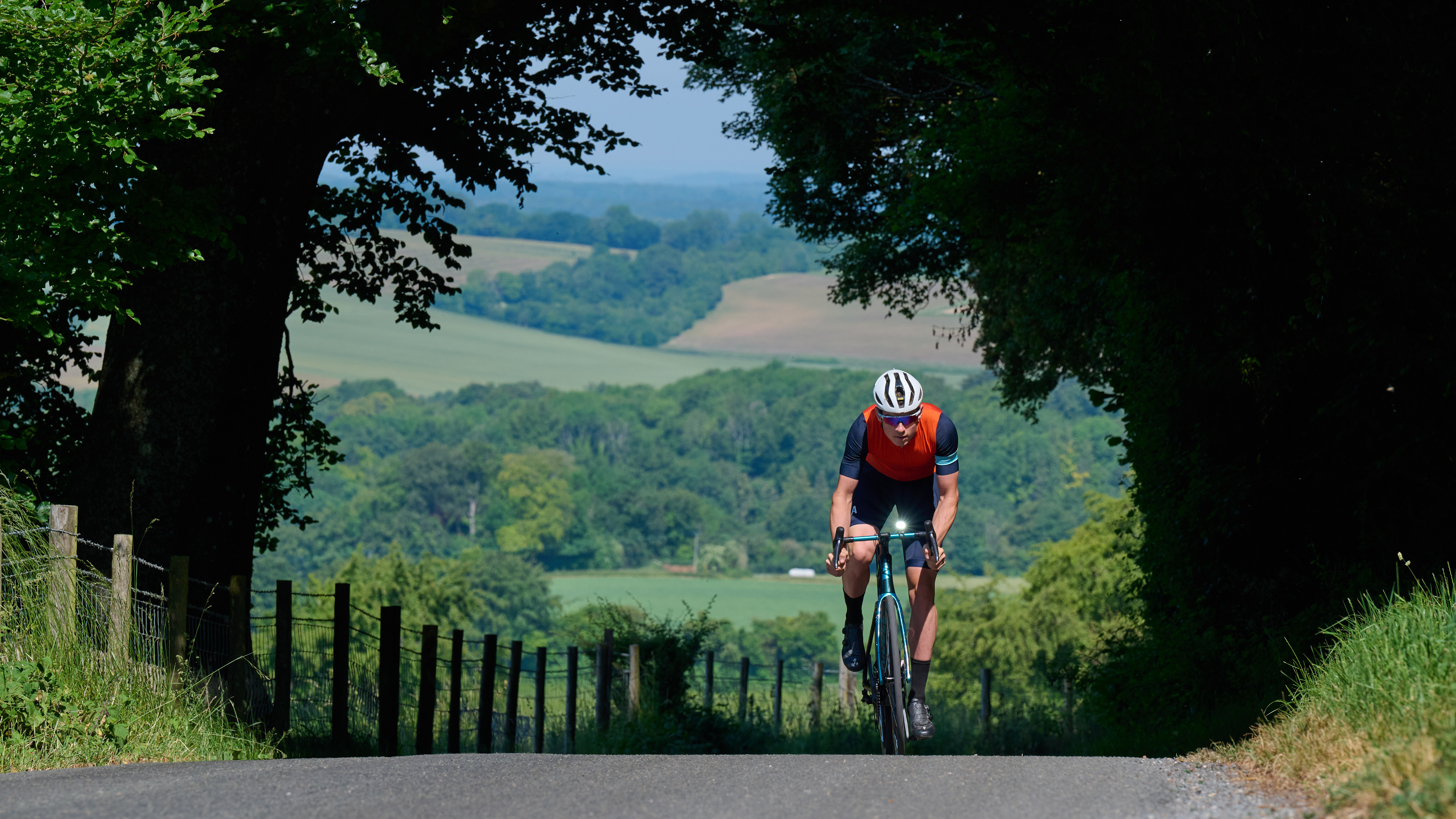 Cyclist riding on a bright sunny day utilizing daylight running modes to still be seen 