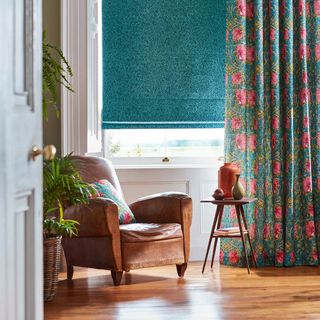 Window with teal blind and floral curtains