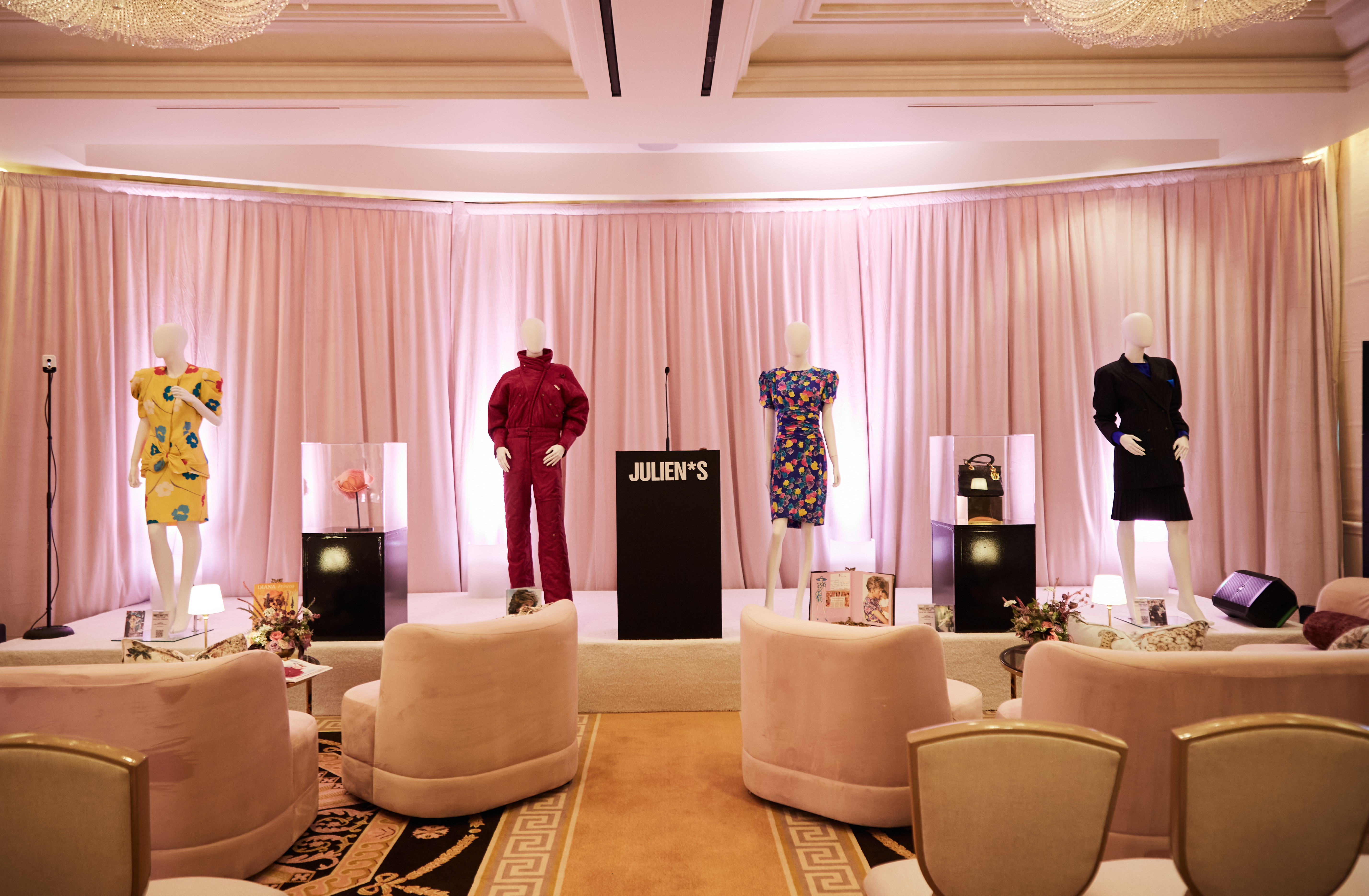 Mannequins wearing Princess Diana outfits in a room with a podium
