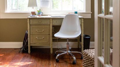 A white office chair tucked underneath a desk.