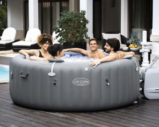 four people sitting in an inflatable hot tub on a deck